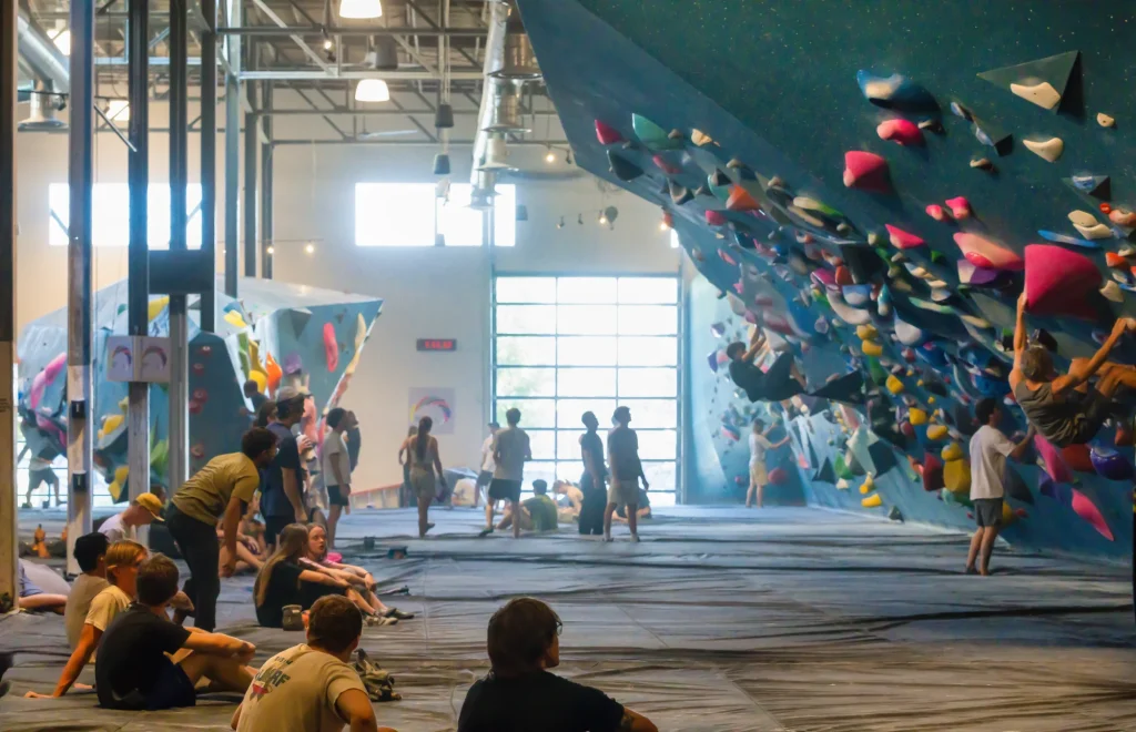 Climbers and spectators inside a large indoor bouldering gym