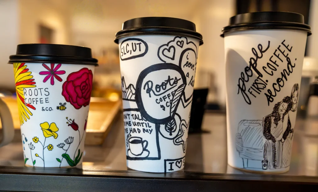 Three decorated Roots Coffee & Co. to-go cups