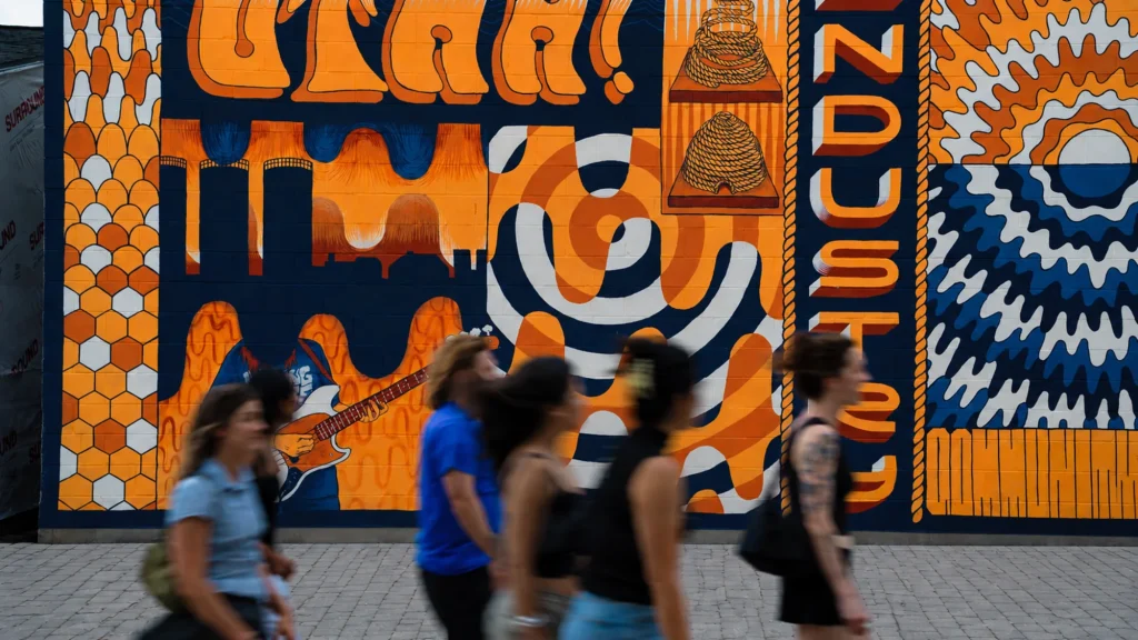 People walking past a colorful Utah-themed street mural