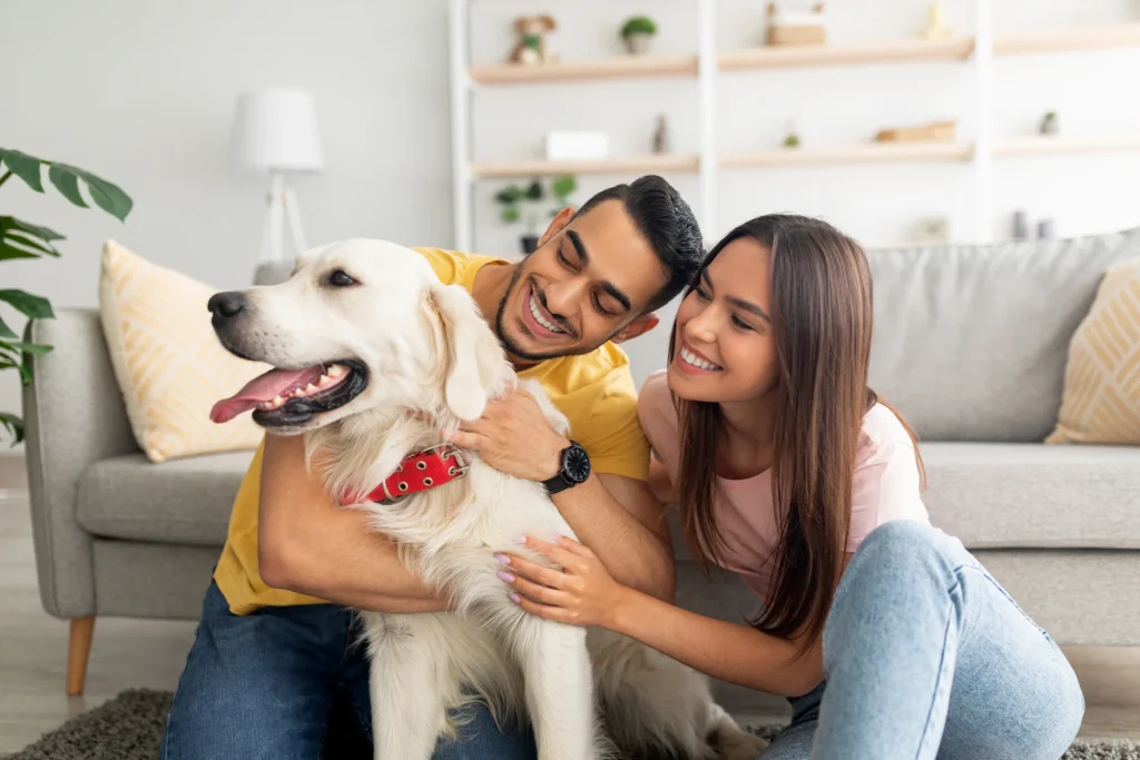 Happy couple cuddling their golden retriever dog at home