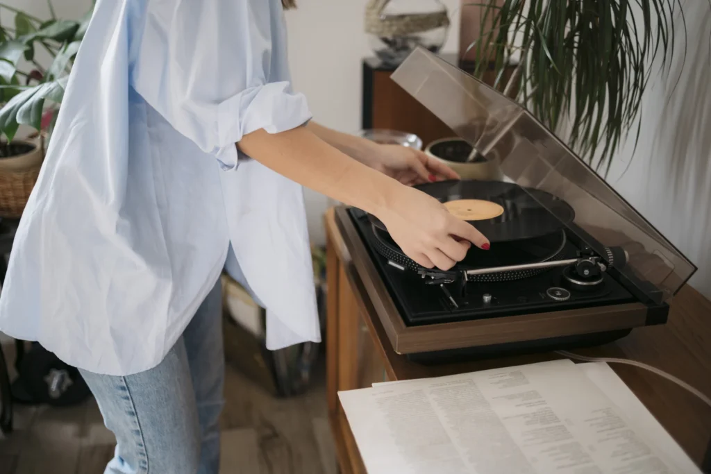 Woman placing vinyl record on turntable at home