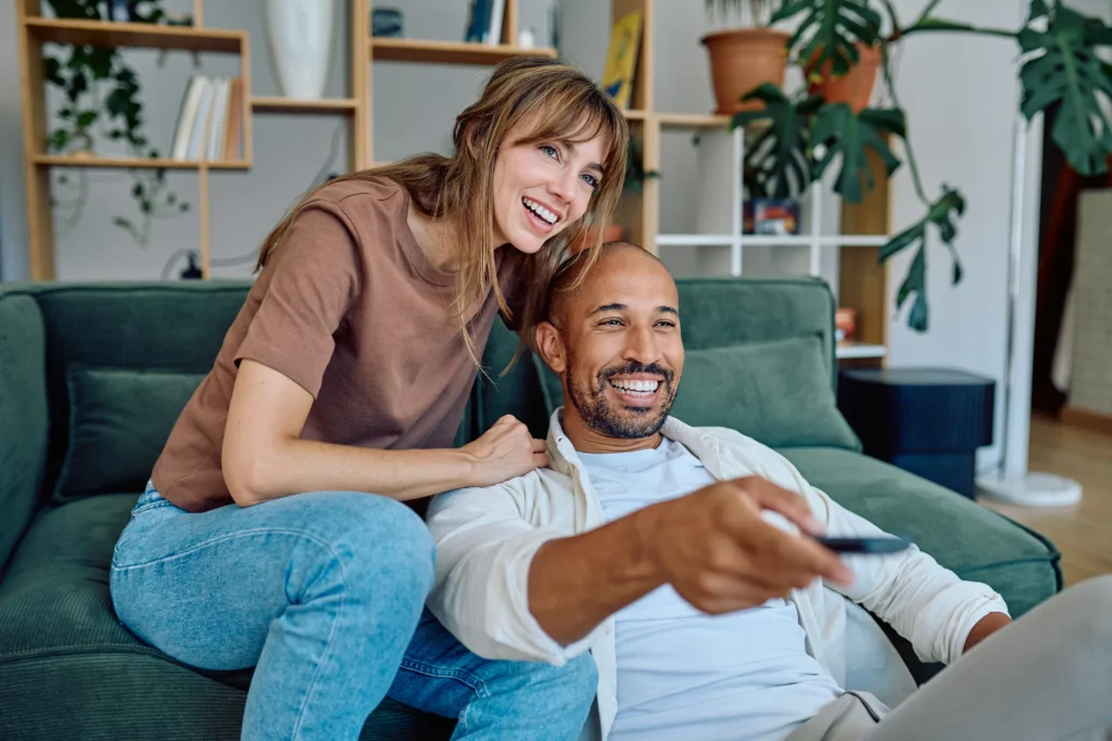 Happy couple relaxing on couch watching TV with remote