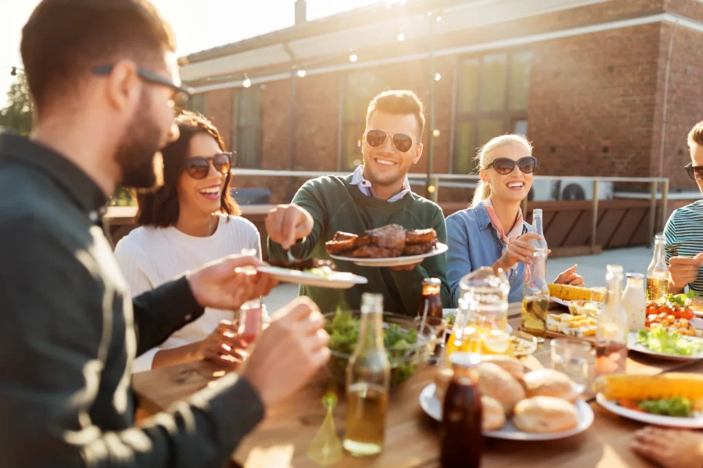 Friends enjoying outdoor rooftop barbecue party with food and drinks