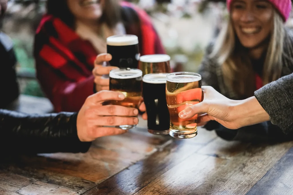 Friends toasting with beer glasses at a wooden pub table