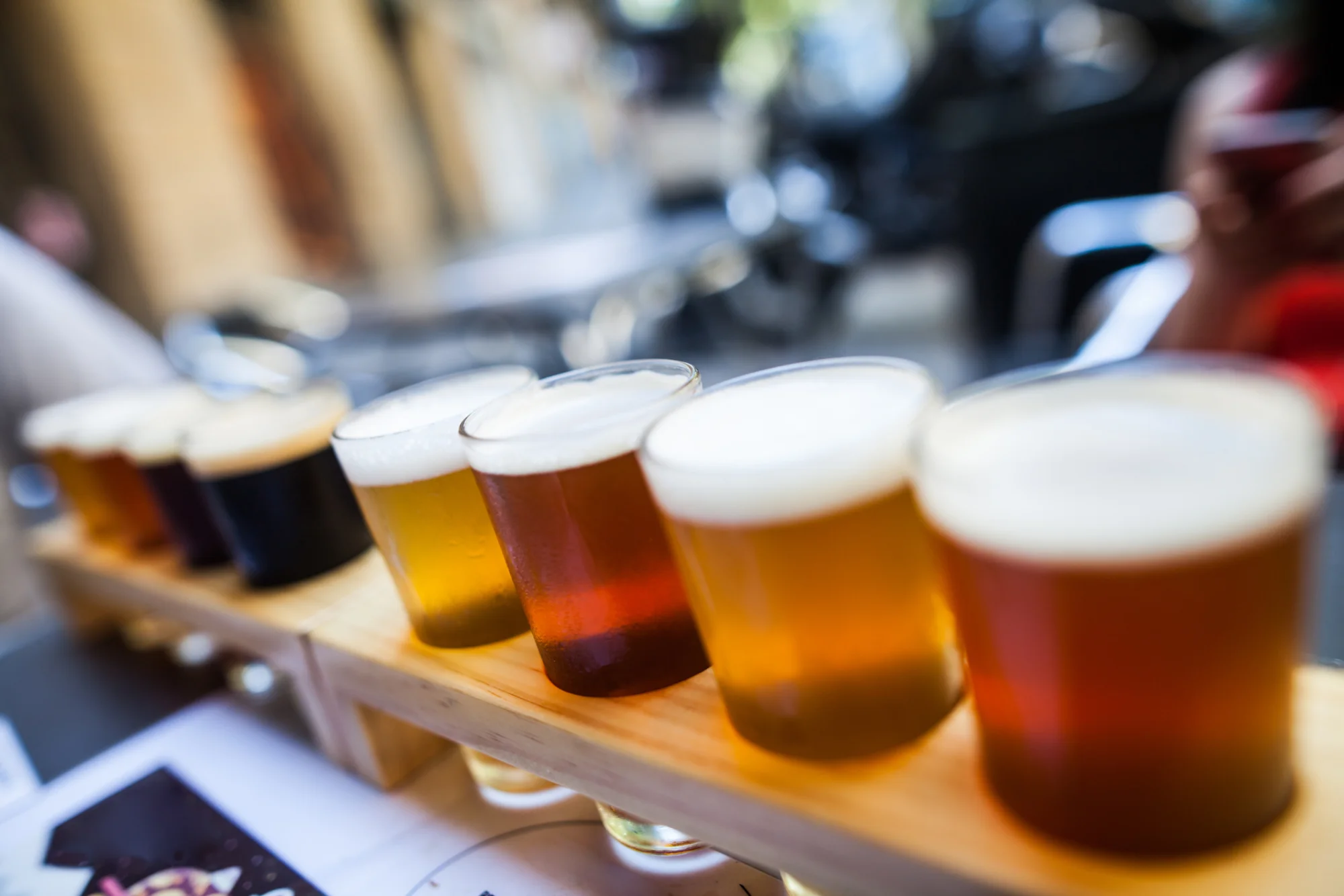 Craft beer flight sampler with various ales on wooden board